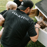 Man wearing a black Grit & Giants embroidered dad hat outdoors with his children.