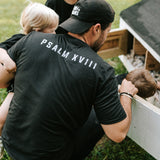 Man wearing a black Grit & Giants embroidered dad hat outdoors with his children.