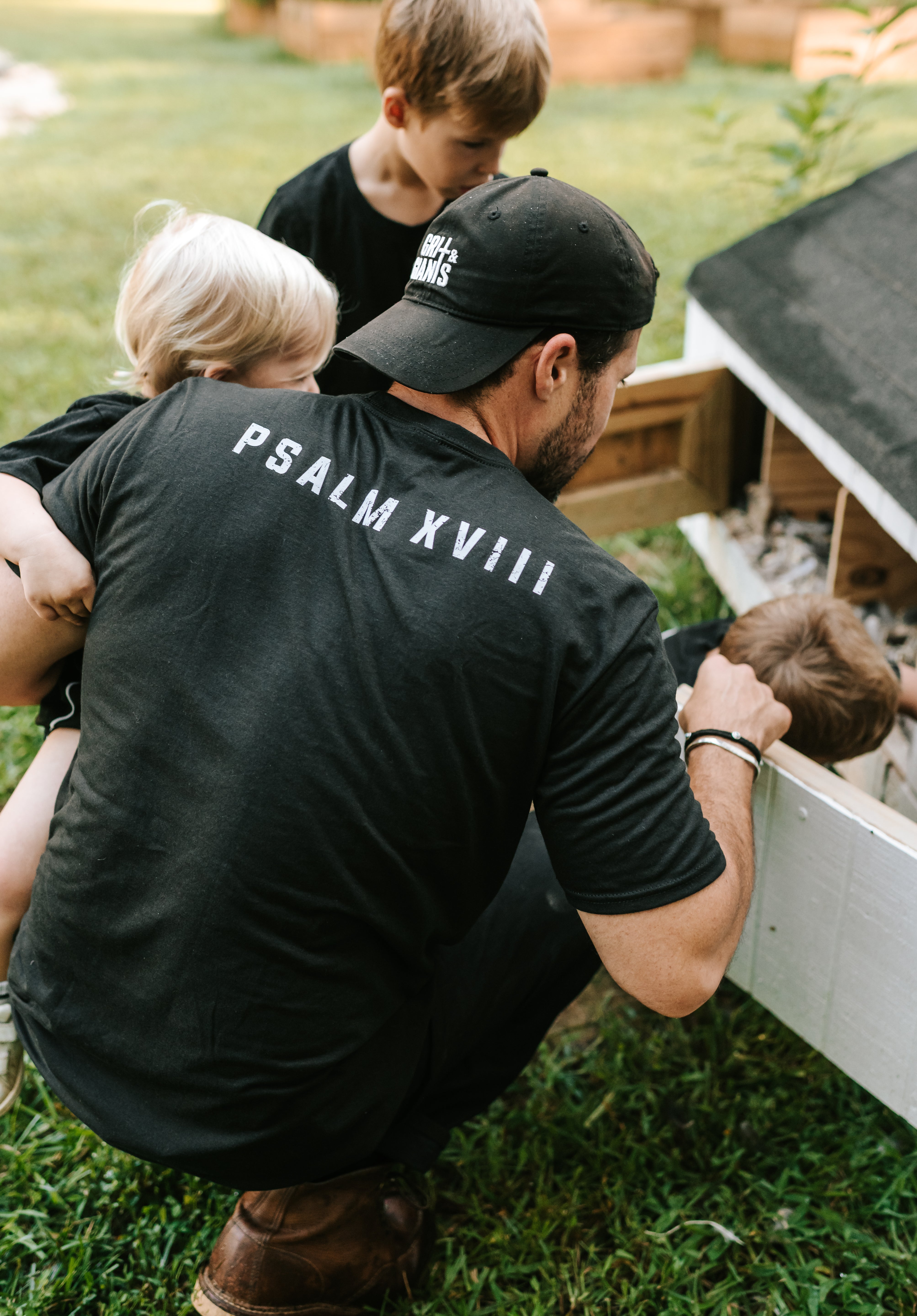 Man wearing a black Grit & Giants embroidered dad hat outdoors with his children.