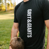 Father wearing a black Grit & Giants Refuge Training Tee outdoors with his son.