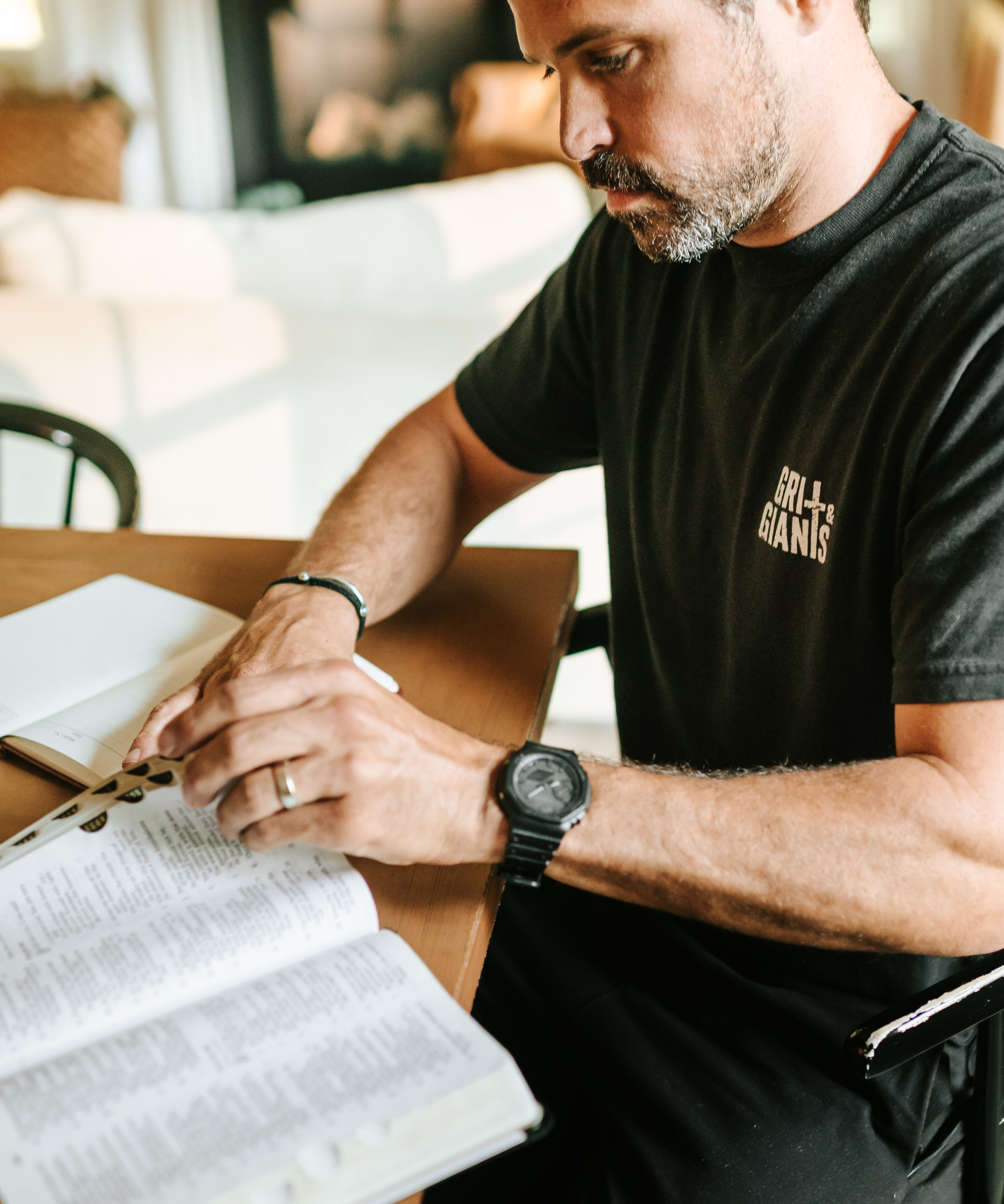 Man wearing a black Grit & Giants Signature Tee while reading the Bible during a morning devotional.