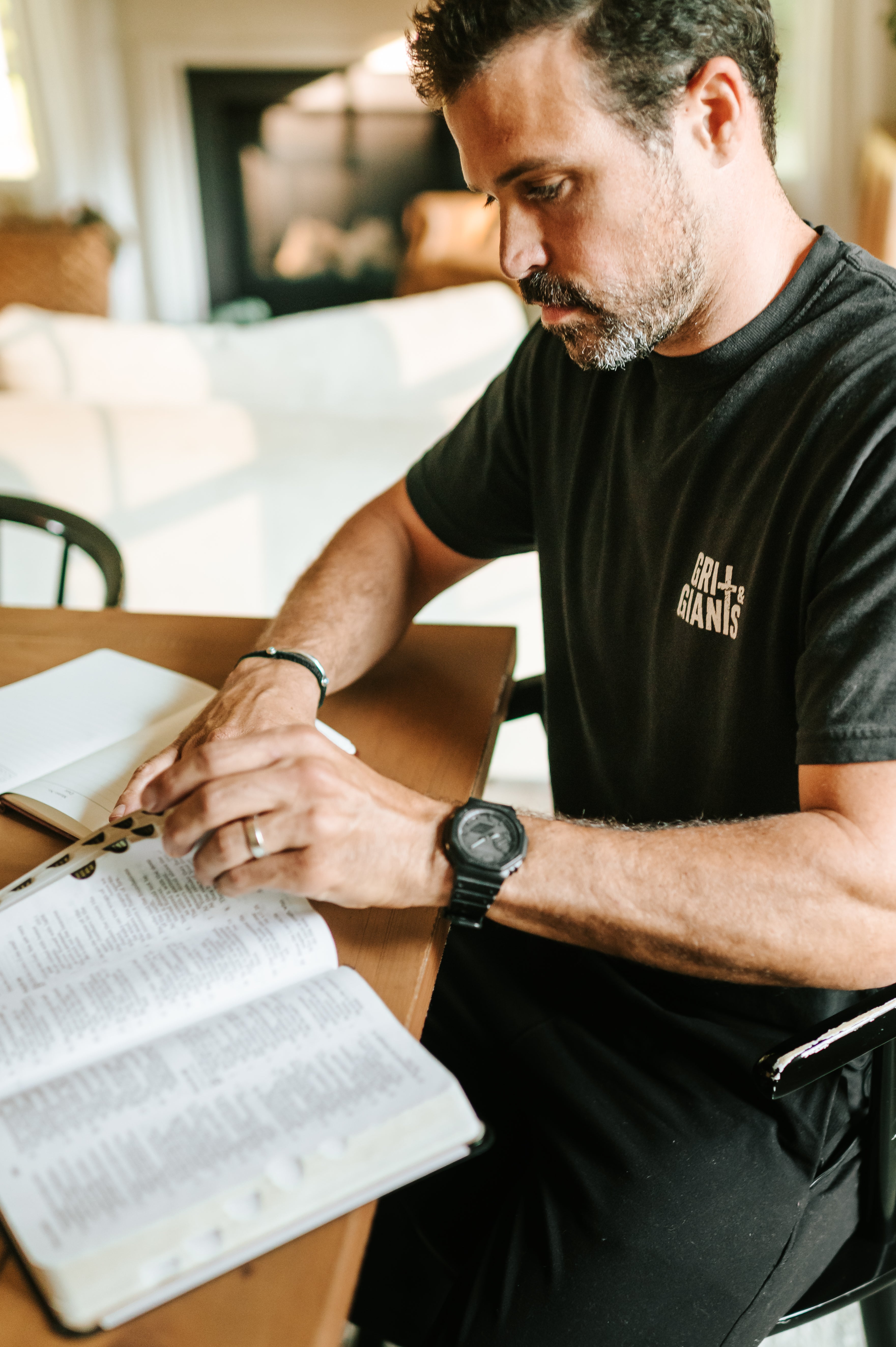 Man wearing a black Grit & Giants Signature Tee while reading the Bible during a morning devotional.