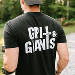 Man lifting dumbbells outdoors wearing a black Grit & Giants Stone Signature Tee with back logo.