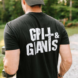 Man lifting dumbbells outdoors wearing a black Grit & Giants Stone Signature Tee with back logo.