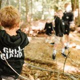 Boy wearing a black Grit & Giants toddler hoodie while exploring the woods.