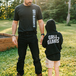 Father standing outdoors with his son wearing a black Grit & Giants youth hoodie.