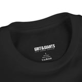 Close-up of the printed Grit & Giants neck label inside a black youth tee.