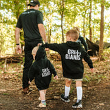 Two boys wearing black Grit & Giants youth and toddler hoodies while walking through the woods.